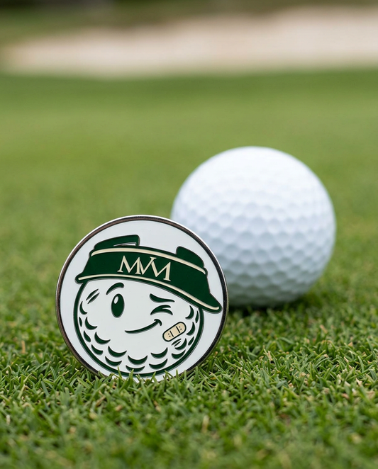 Mulligan golf ball marker in forest green and cream print on a putting green next to a golf ball