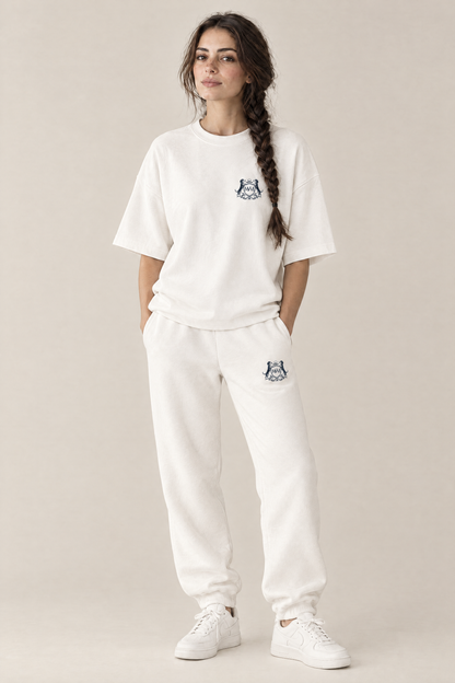 Woman in a white oversized Club Crest tee and matching white sweatpants, full body, tone-on-tone set