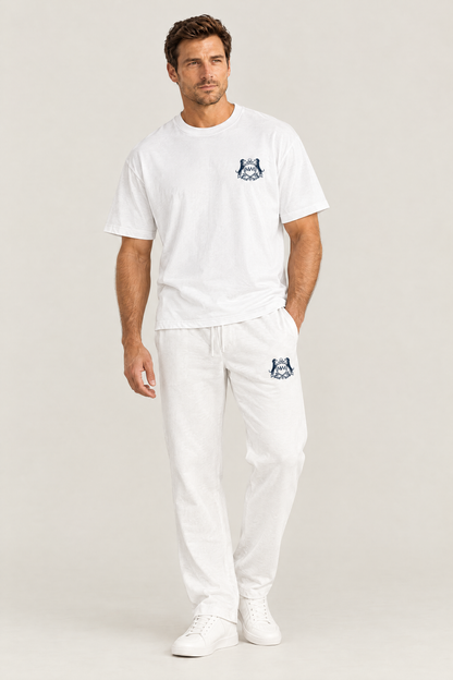 Man in white straight-leg Club Crest sweatpants with the small navy dachshund golf crest on the thigh, full body