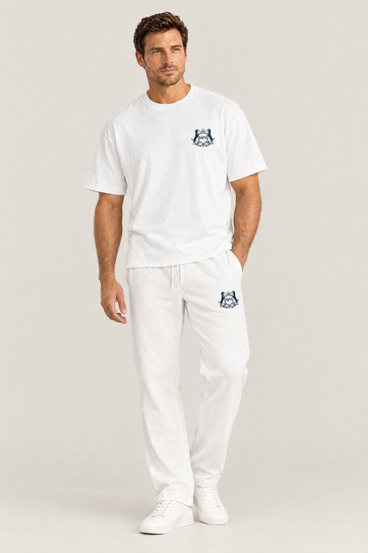 Man in white straight-leg Club Crest sweatpants with the small navy dachshund golf crest on the thigh, full body