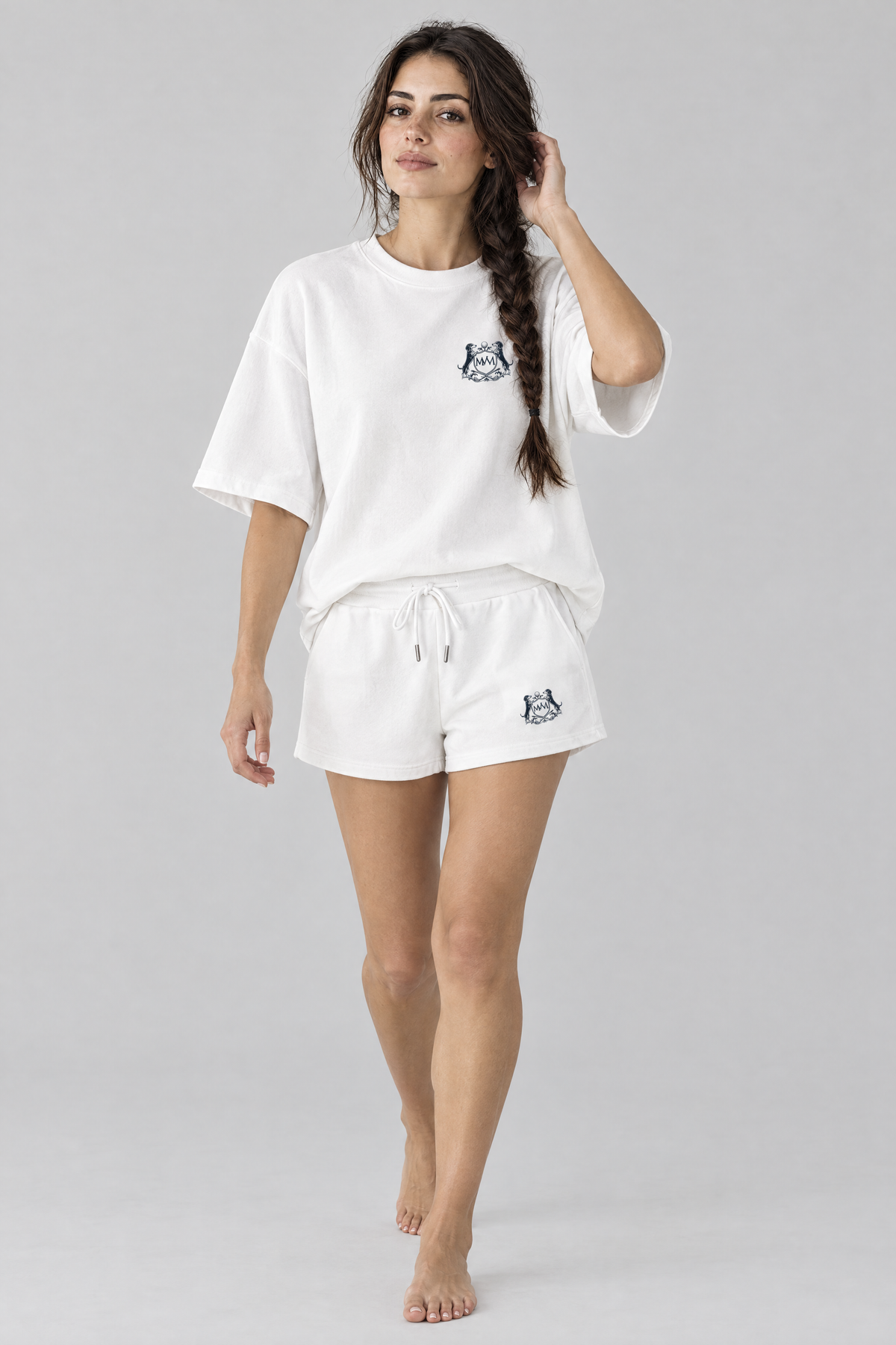 Woman walking in white Club Crest drawstring shorts and a white Club Crest tee, full body, tone-on-tone set. Color: White