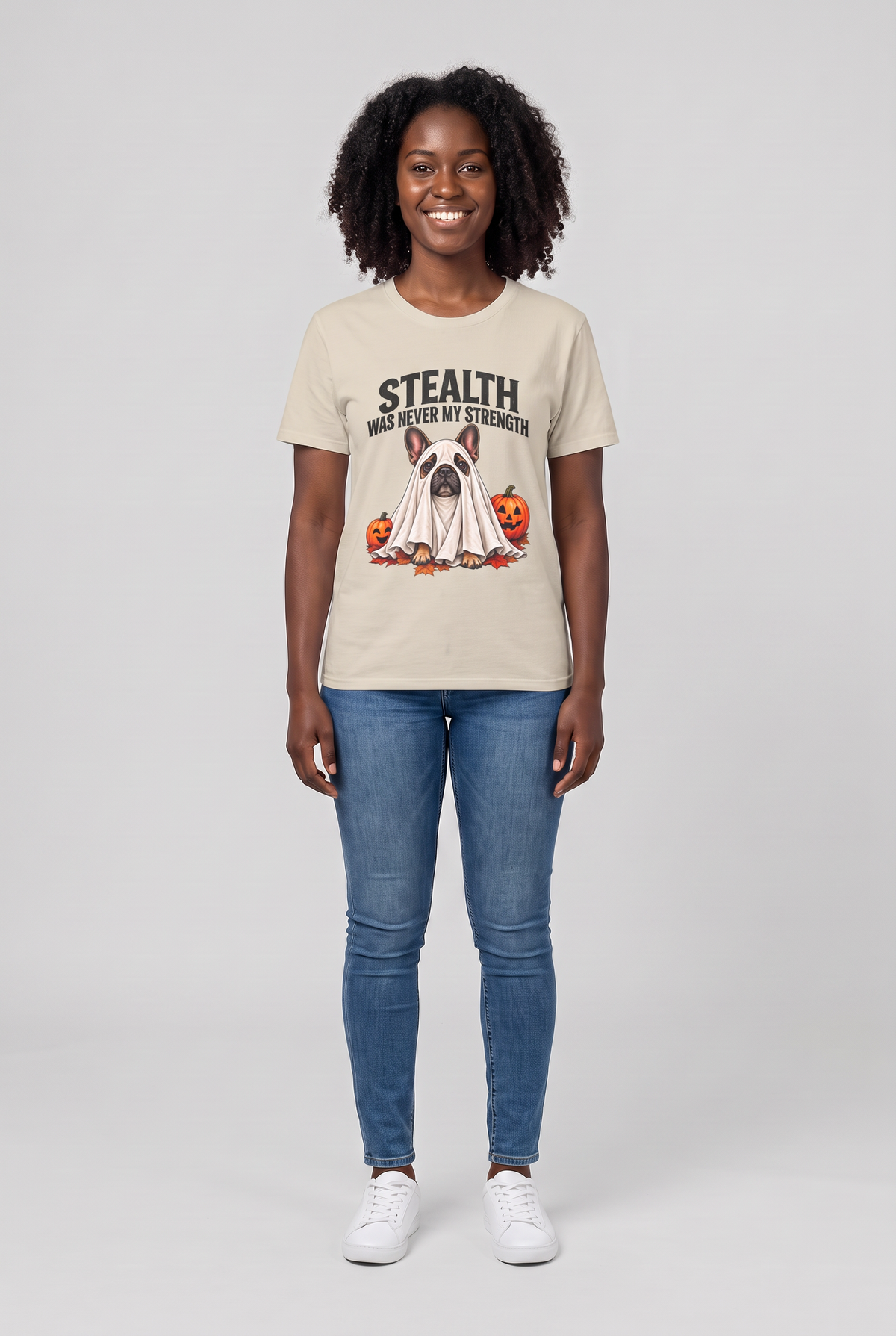 Frau trägt ein Französische Bulldogge Halloween T-Shirt in Sand mit Frenchie-Gespenst und dem Spruch Stealth Was Never My Strength, Vorderansicht