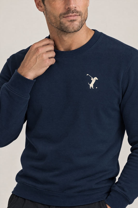 Close-up of man touching the collar of a navy Swing dachshund golf sweatshirt, chest print detail. Color: Navy