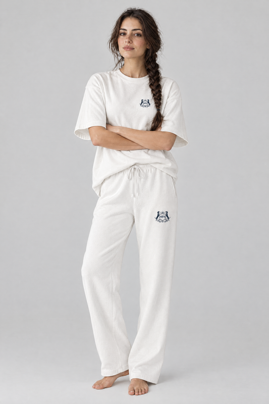 Woman standing with arms crossed in white Club Crest sweatpants and a white tee, full body, tone-on-tone set