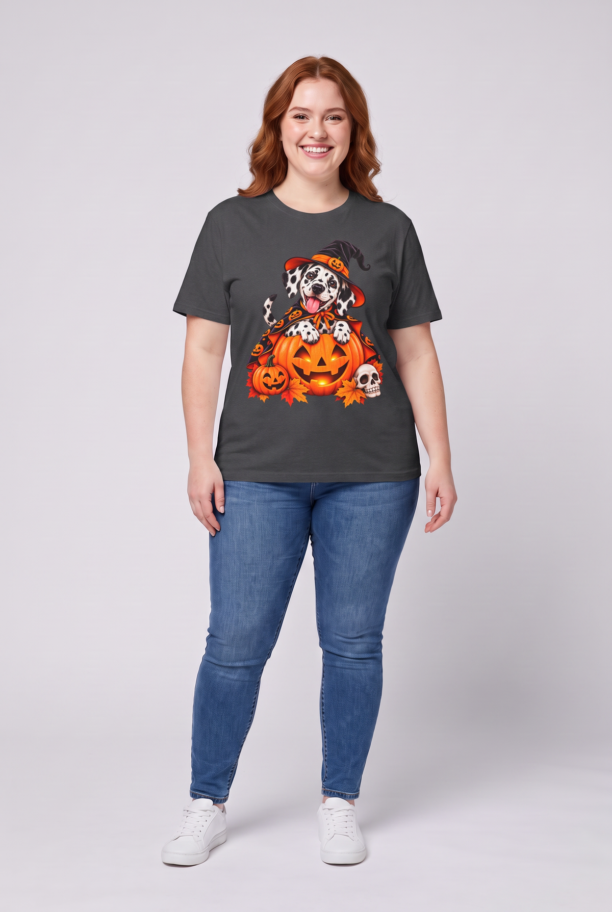 Frau trägt ein Dalmatiner Hexen Halloween T-Shirt in Dark Heather mit Dalmatiner in Hexenhut und Kürbis-Umhang auf einer Kürbislaterne, Vorderansicht