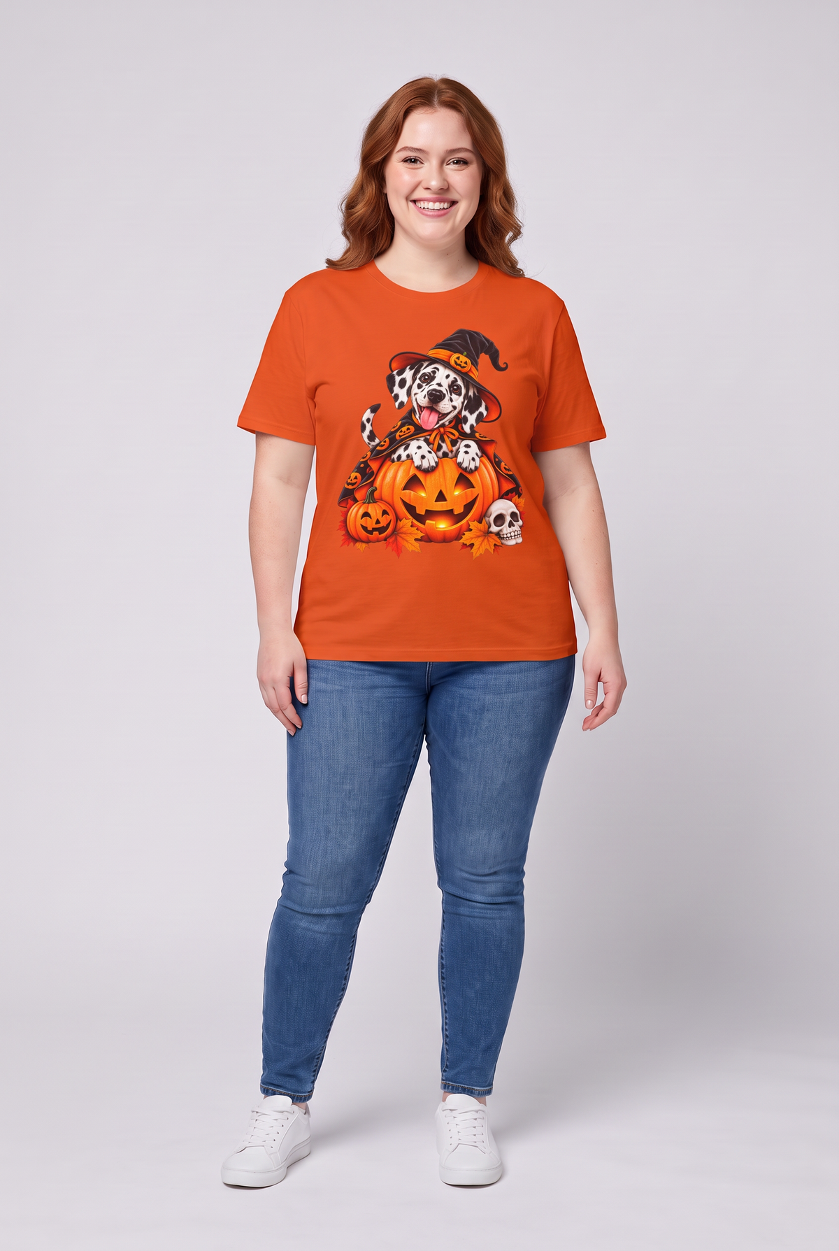 Frau trägt ein Dalmatiner Hexen Halloween T-Shirt in Orange mit Dalmatiner in Hexenhut und Kürbis-Umhang auf einer Kürbislaterne, Vorderansicht