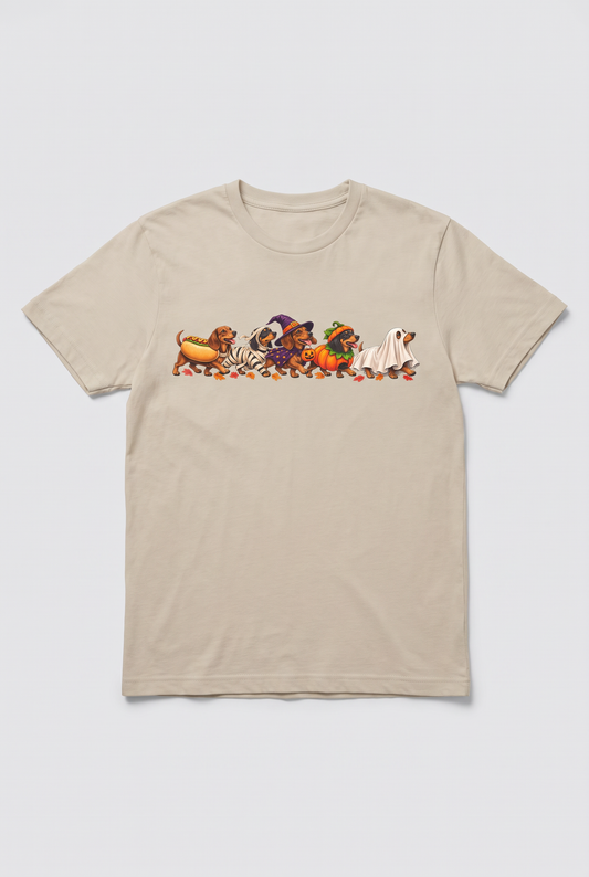 Flat lay of a sand wiener dog Halloween parade t-shirt with five dachshunds dressed as hot dog, mummy, witch, pumpkin and ghost
