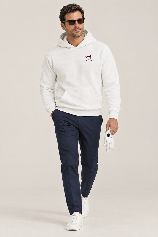 Man in dark sunglasses walking in white Club & Swing dachshund golf hoodie and navy trousers, holding a golf glove, full-body studio look. Color: White