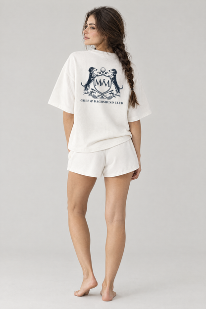 Back view of a woman in white Club Crest shorts and a white tee with a large navy crest on the back. Color: White