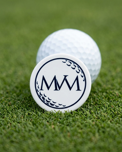 Pure Ball golf ball marker in navy and cream print on a putting green next to a golf ball
