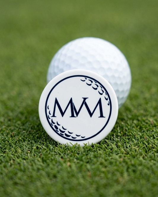 Pure Ball golf ball marker in navy and cream print on a putting green next to a golf ball