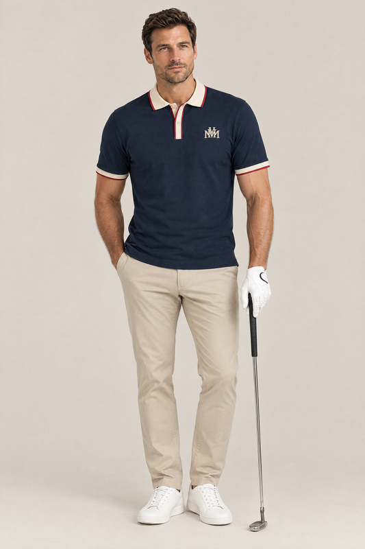 Man wearing the navy Club Crest color block polo with apricot trim, golf glove and putter, full body. Color: Navy Blue with Apricot
