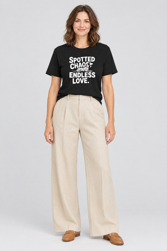Woman wearing the black Spotted Chaos Dalmatian t-shirt with beige wide-leg trousers. Color: Black