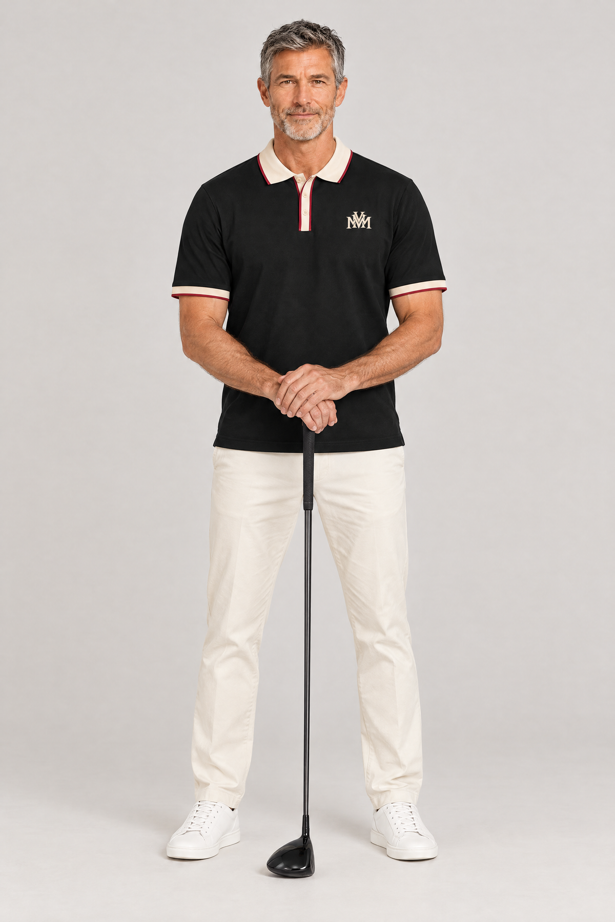 Man in the black Club Crest color block polo with apricot trim, hands resting on a golf driver. Color: Black with Apricot