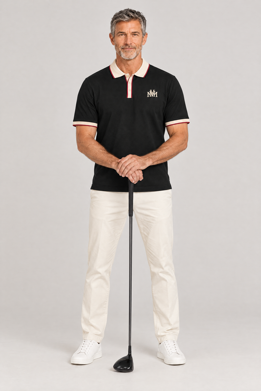 Man in the black Club Crest color block polo with apricot trim, hands resting on a golf driver. Color: Black with Apricot