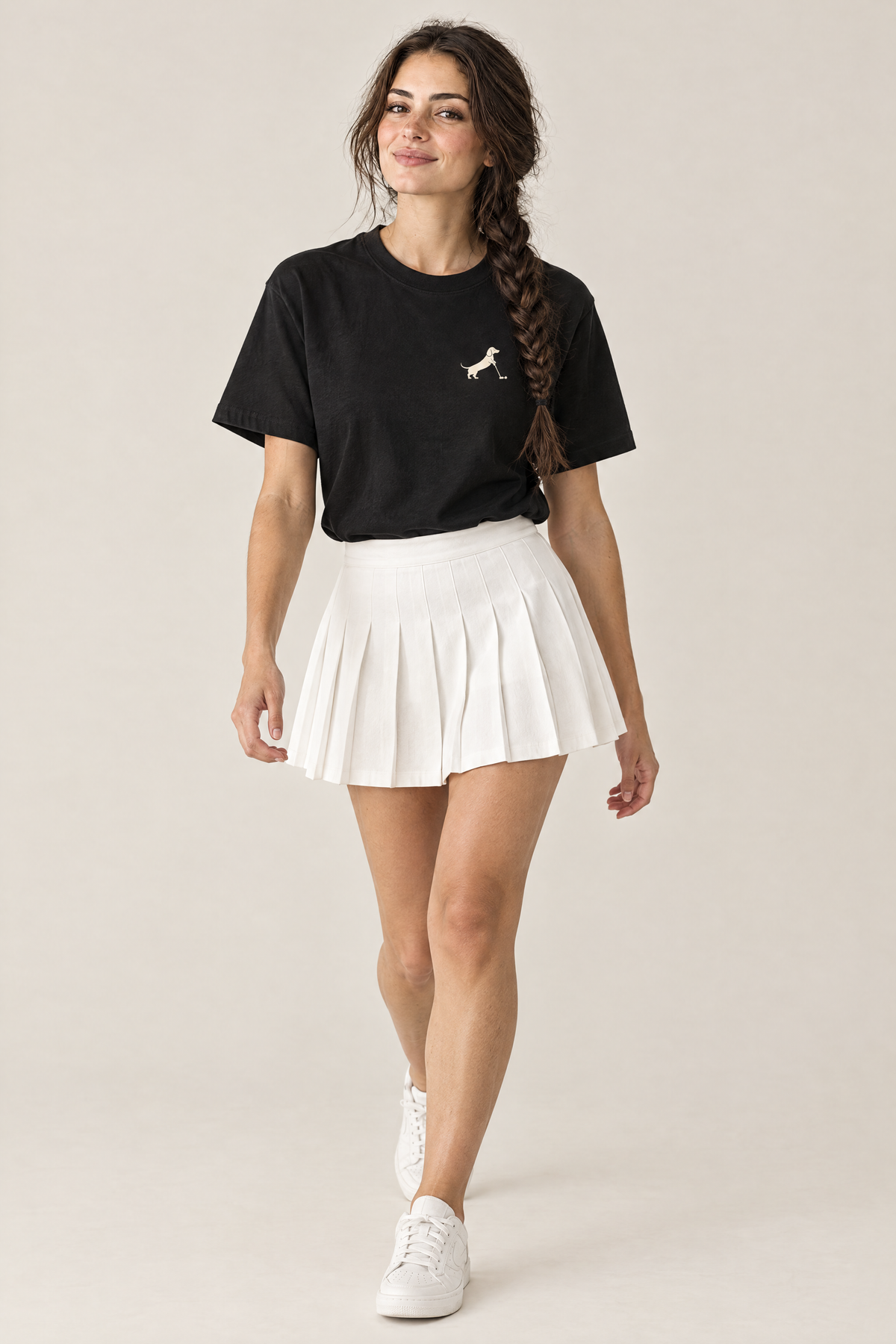 Woman walking in black Putting dachshund golf t-shirt tucked into a white pleated skirt, three-quarter view. Color: Black