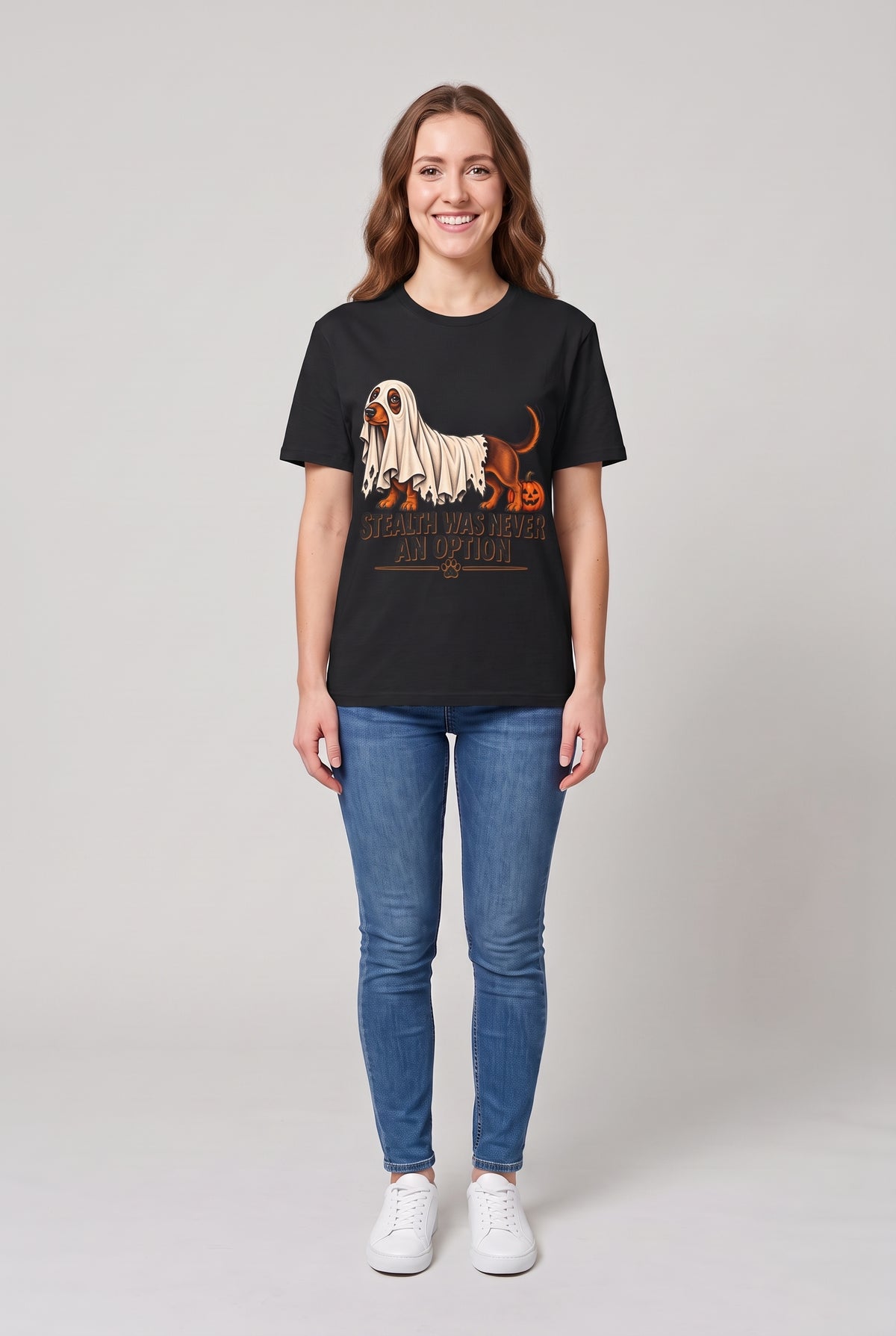 Frau trägt ein Dackel Halloween T-Shirt in Schwarz mit Dackel unter einem zu kurzen Gespensterlaken und dem Spruch Stealth Was Never An Option, Vorderansicht