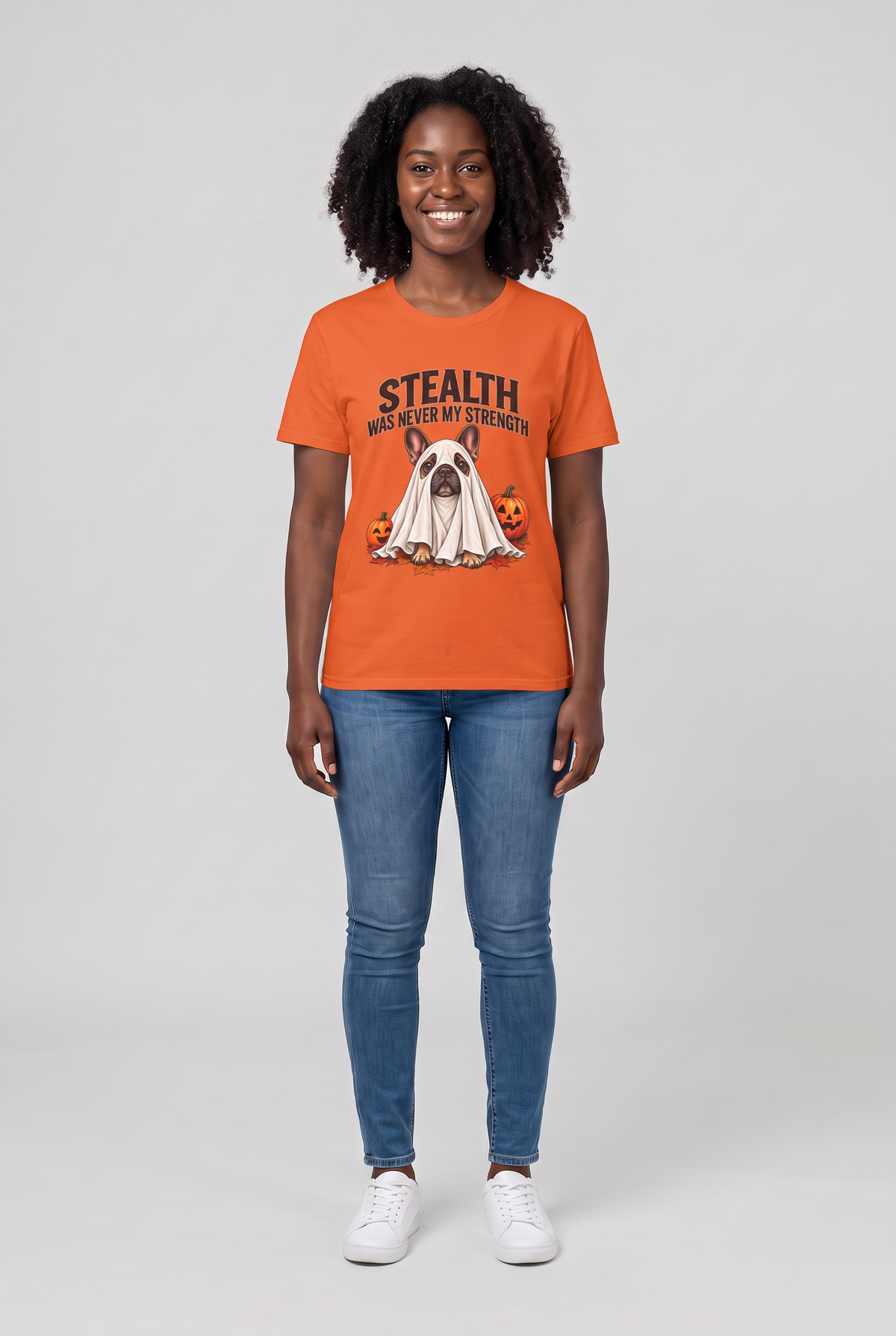 Frau trägt ein Französische Bulldogge Halloween T-Shirt in Orange mit Frenchie-Gespenst und dem Spruch Stealth Was Never My Strength, Vorderansicht