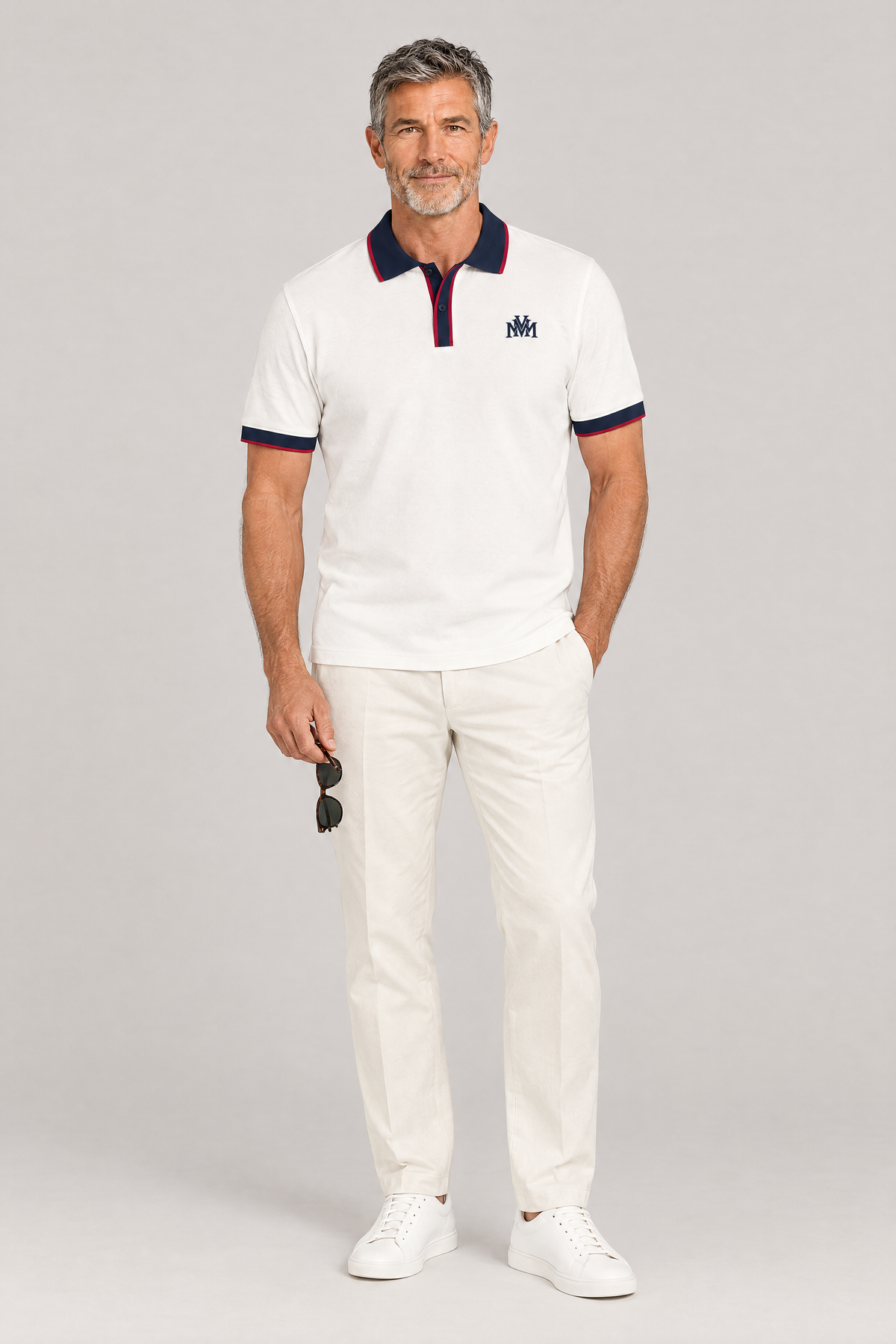 Man wearing the white Club Crest color block polo with navy trim, holding sunglasses, full body. Color: White with Navy Blue