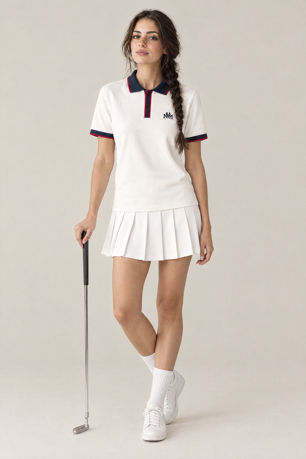 Woman wearing the Club Crest color block polo in white with navy trim and a pleated golf skirt, holding a putter. Color: White with Navy Blue