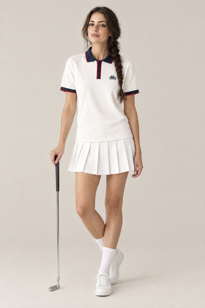Woman wearing the Club Crest color block polo in white with navy trim and a pleated golf skirt, holding a putter. Color: White with Navy Blue