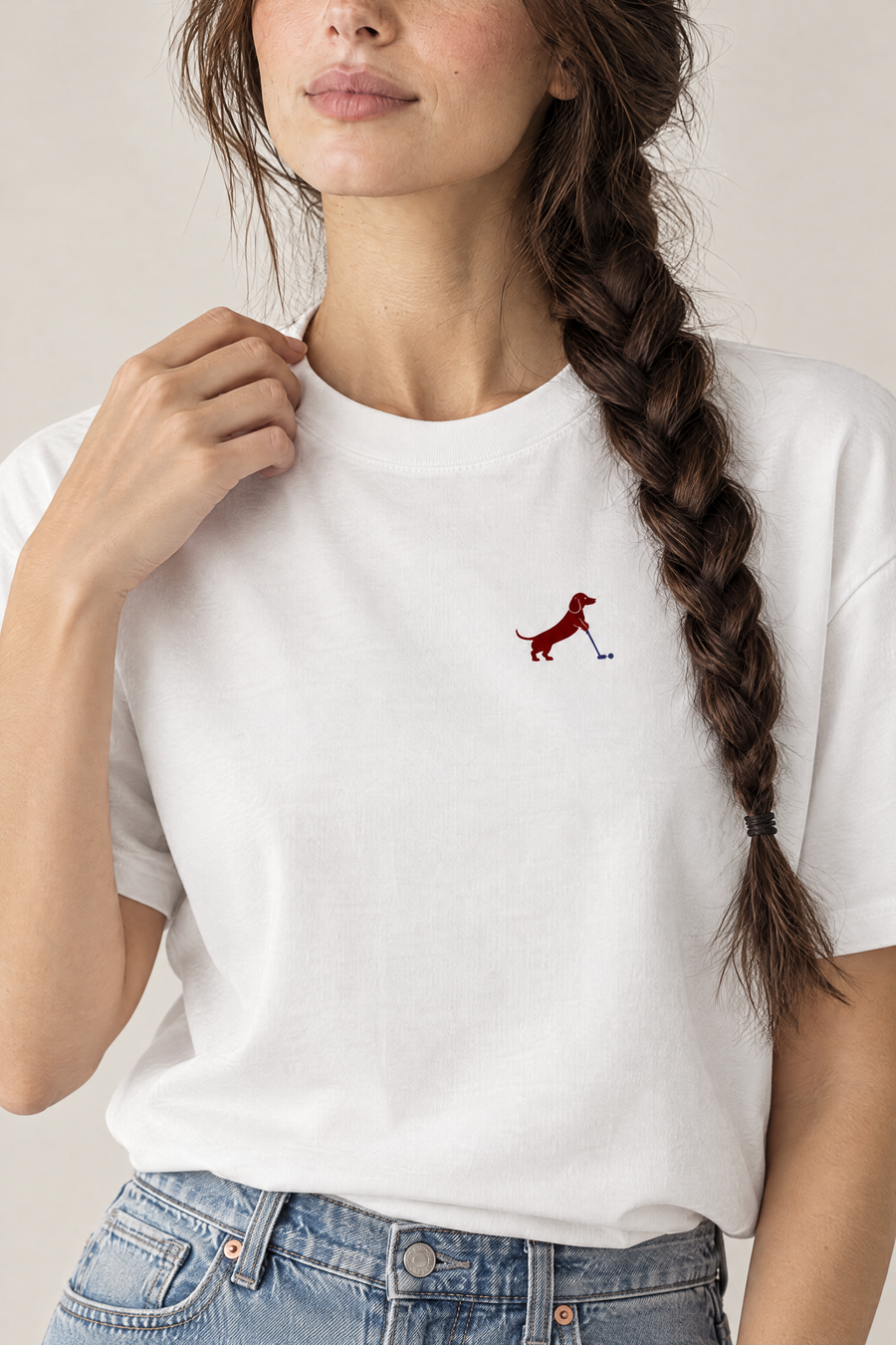 Close-up of woman touching the collar of a white Putting dachshund golf t-shirt, chest print detail. Color: White