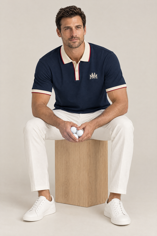 Man sitting on a wooden box in the navy Club Crest polo with apricot trim, holding golf balls. Color: Navy Blue with Apricot