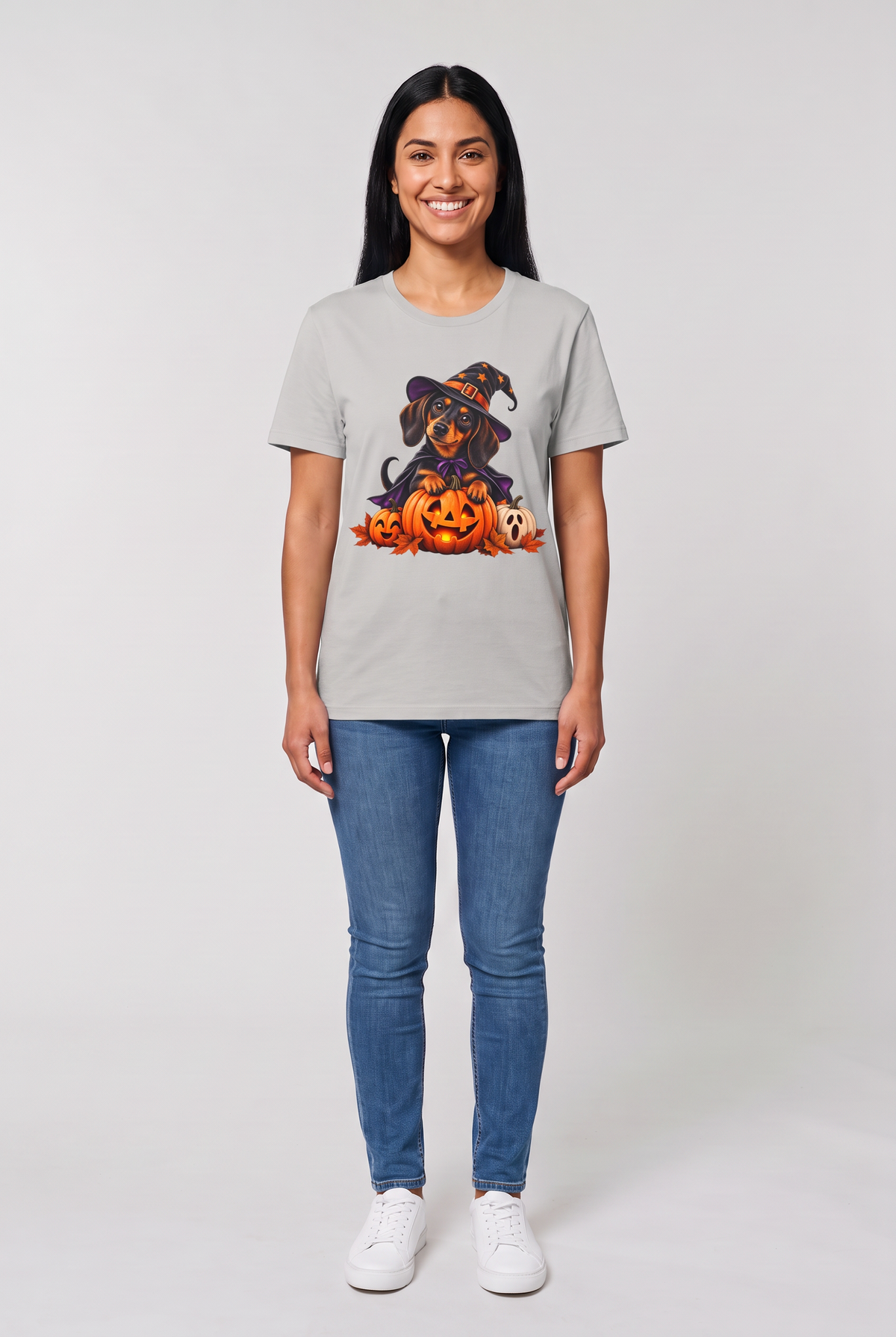 Frau trägt ein Dackel Hexen Halloween T-Shirt in Ice Grey mit Dackel in Hexenhut und Umhang auf einer leuchtenden Kürbislaterne, Vorderansicht