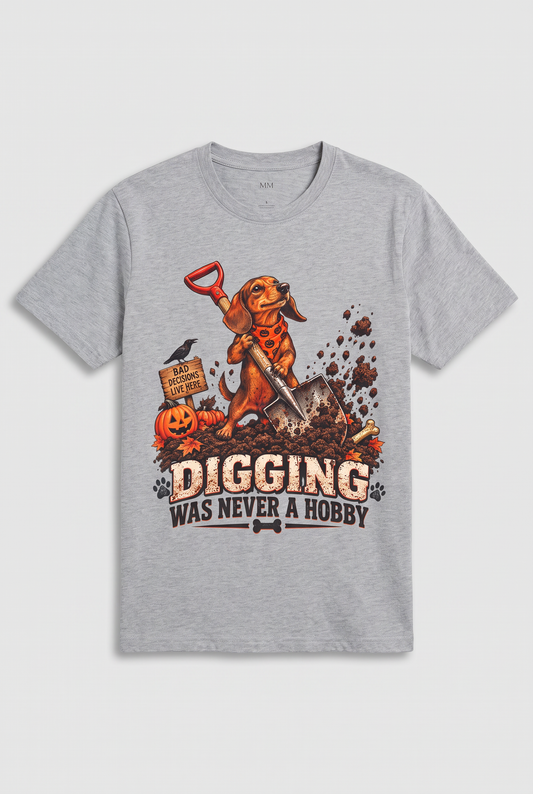 Flat lay of a sport grey funny dachshund Halloween t-shirt with a digging wiener dog and the text Digging Was Never A Hobby