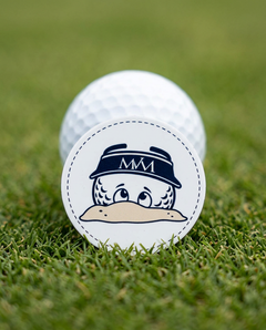 Bunker Buddy golf ball marker in navy and cream print on a putting green next to a golf ball