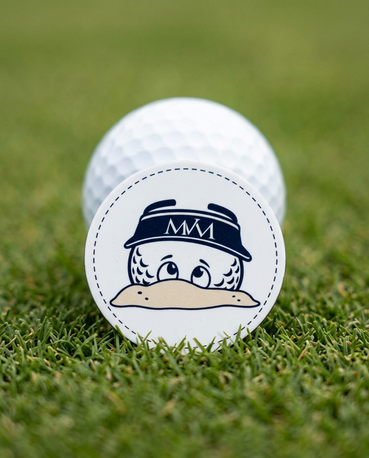 Bunker Buddy golf ball marker in navy and cream print on a putting green next to a golf ball
