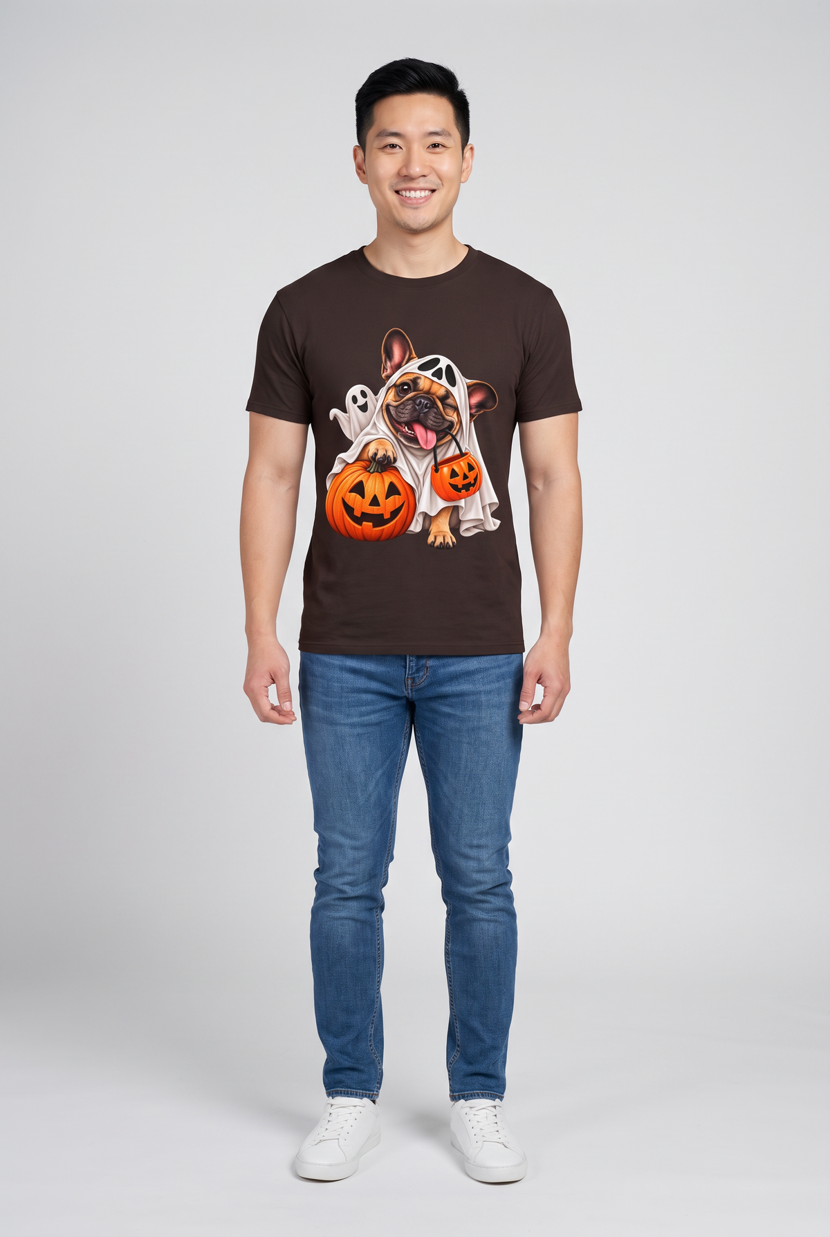 Mann trägt ein Frenchie Gespenster Halloween T-Shirt in Dark Chocolate mit Französischer Bulldogge im Gespensterkostüm und Kürbis-Süssigkeiteneimer, Vorderansicht