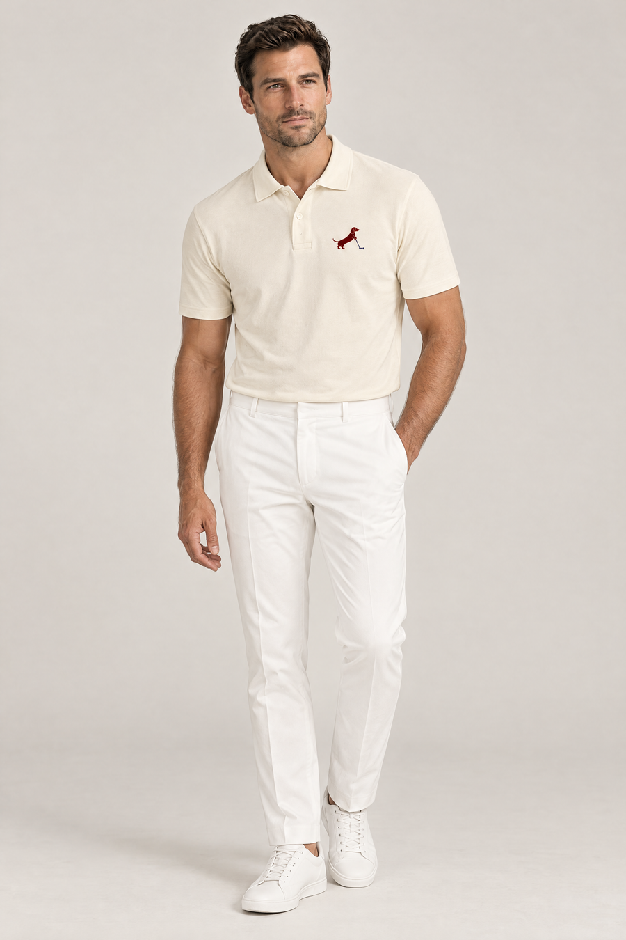 Man standing relaxed with one hand in his pocket wearing apricot Putting dachshund golf polo and white trousers, full-body studio look. Color: Apricot