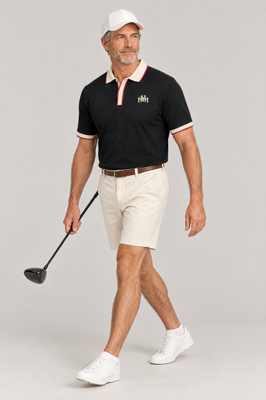 Man walking with a driver in the black Club Crest polo with apricot trim, cream golf shorts and a white cap. Color: Black with Apricot