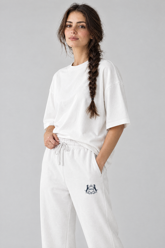 Woman in white Club Crest sweatpants, three-quarter view with a hand on the drawstring waistband