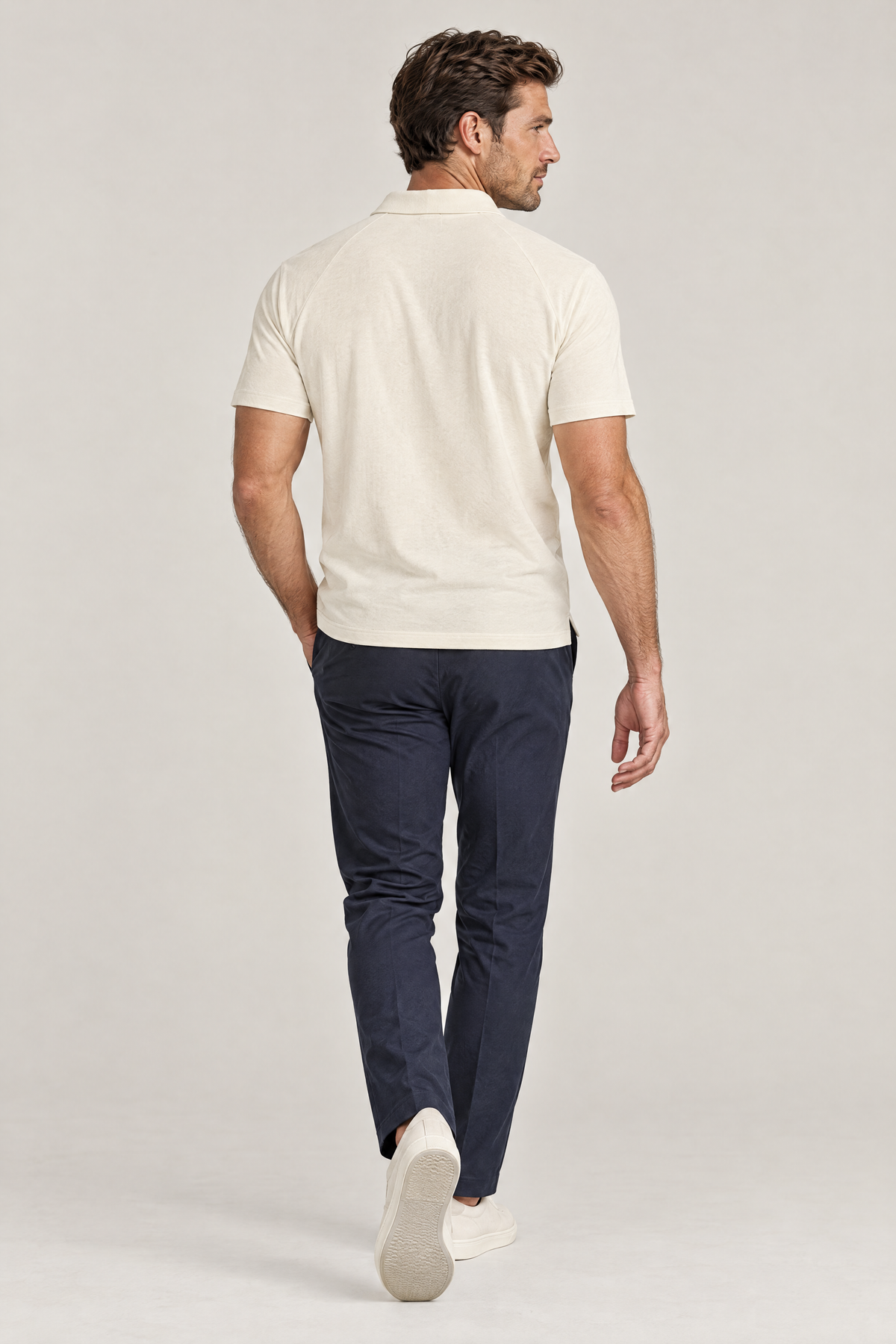 Man seen from behind walking away in apricot Putting dachshund golf polo and navy trousers. Color: Apricot