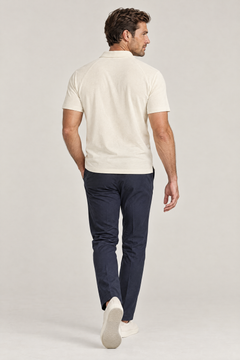 Man seen from behind walking away in apricot Putting dachshund golf polo and navy trousers. Color: Apricot