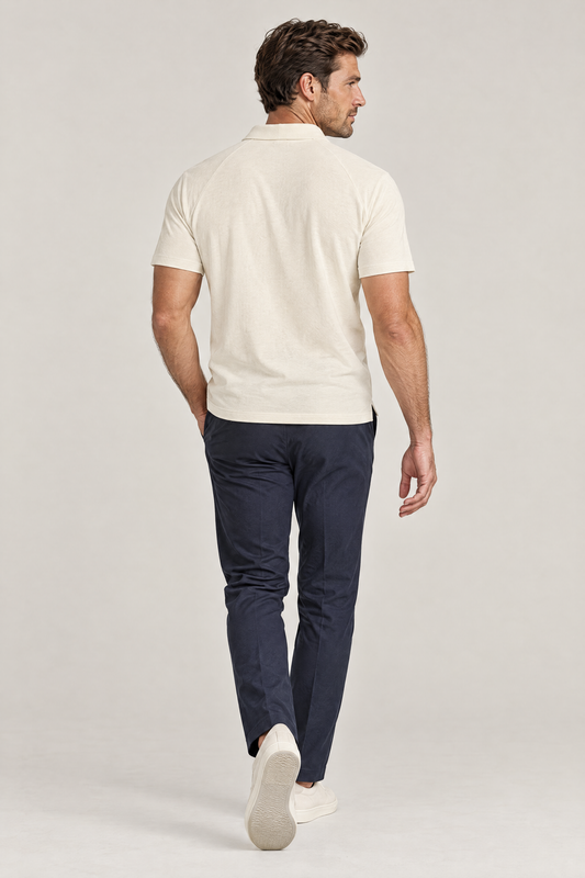 Man seen from behind walking away in apricot Putting dachshund golf polo and navy trousers. Color: Apricot