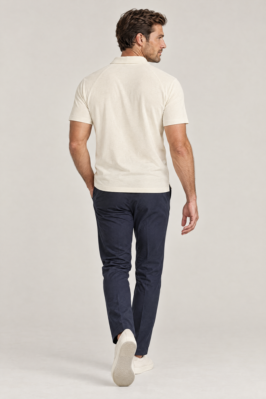 Man seen from behind walking away in apricot Putting dachshund golf polo and navy trousers. Color: Apricot