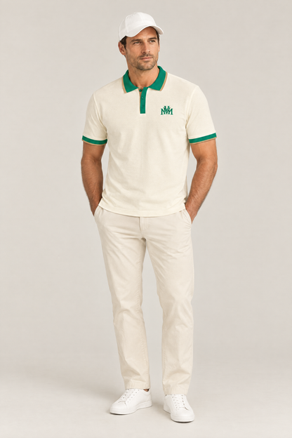 Man wearing the Club Crest color block polo in apricot with green trim, hands in pockets and a white cap. Color: Apricot with Green