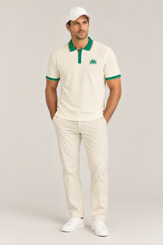 Man wearing the Club Crest color block polo in apricot with green trim, hands in pockets and a white cap. Color: Apricot with Green