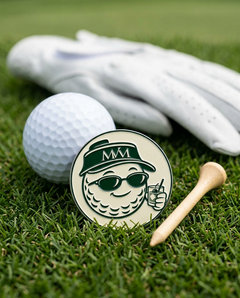 19th Hole golf ball marker in forest green and cream print on grass with a wooden tee and golf glove