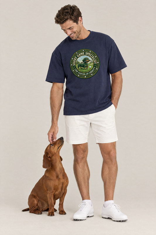 Man wearing the Short Game Crest Dachshund Golf Tee in navy with a red dachshund at his feet. Color: Navy
