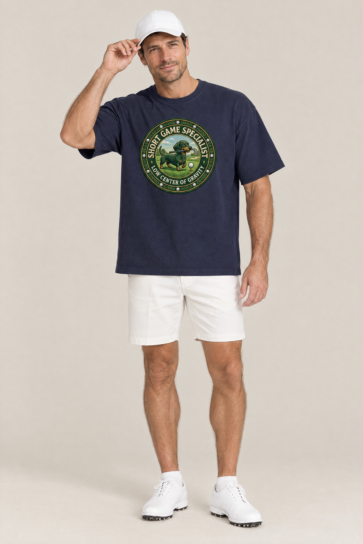 Man wearing the Short Game Crest Dachshund Golf Tee in navy with white golf shorts and a white cap. Color: Navy