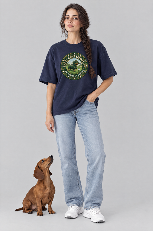 Woman wearing the Short Game Crest Dachshund Golf Tee in navy with a red dachshund at her feet. Color: Navy