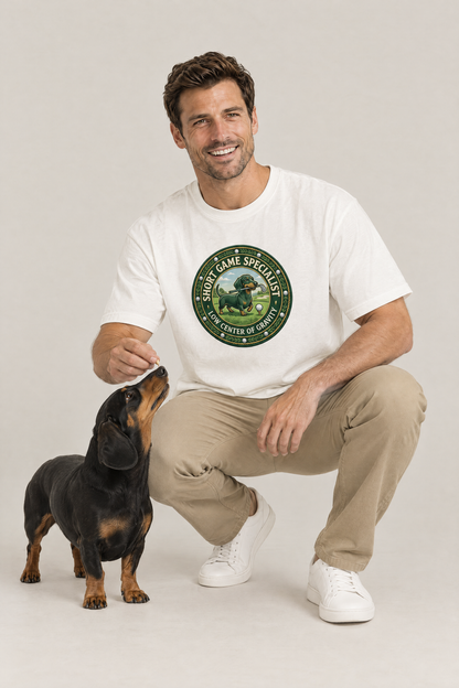 Man crouching with a black and tan dachshund in the white Short Game Crest Dachshund Golf Tee. Color: White