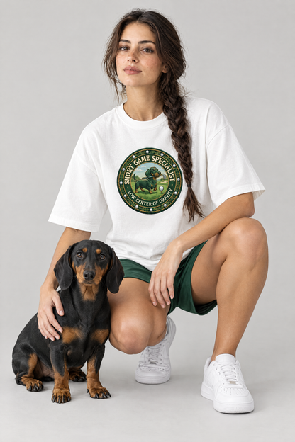 Woman crouching with a black and tan dachshund in the white Short Game Crest Dachshund Golf Tee. Color: White