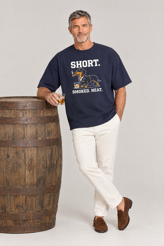 Man leaning on a whisky barrel with a glass in the navy Short Smoked Neat Dachshund Tee. Color: Navy