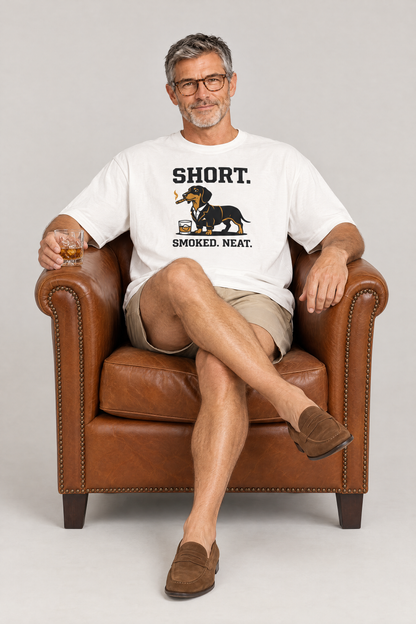 Man relaxing in a leather club chair with a whisky in the white Short Smoked Neat Dachshund Tee. Color: White