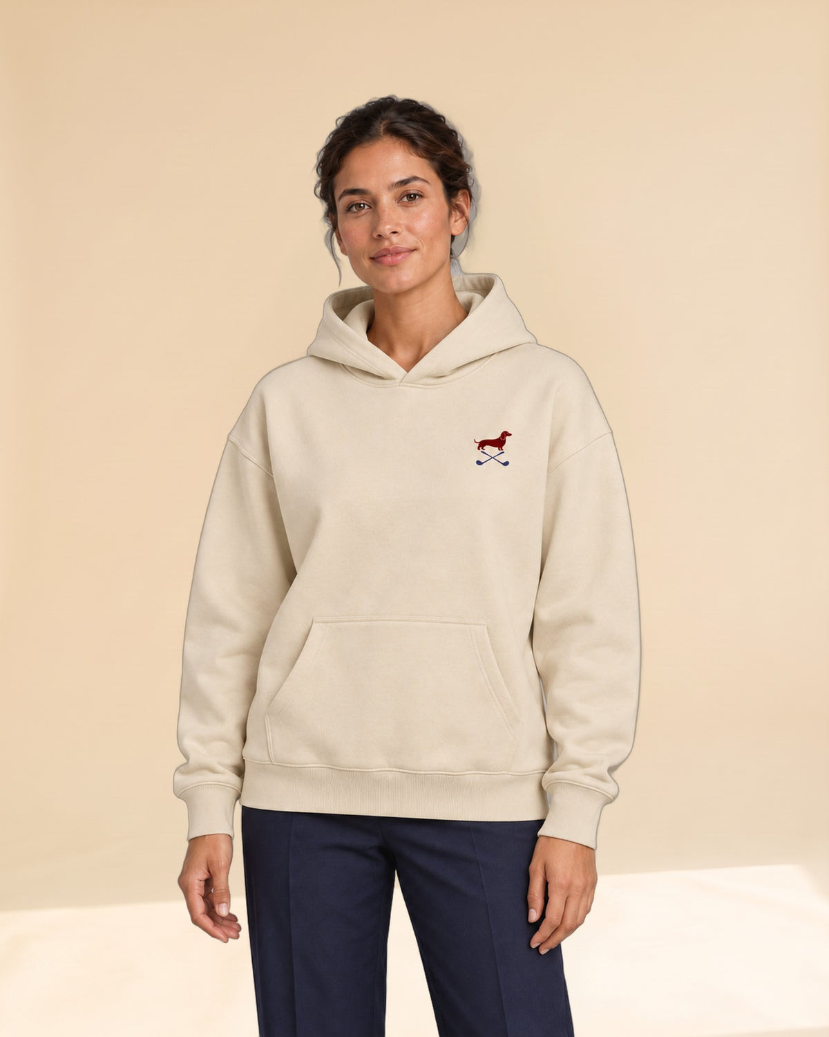 Woman wearing Club & Swing dachshund golf hoodie, front studio view. Color: Apricot